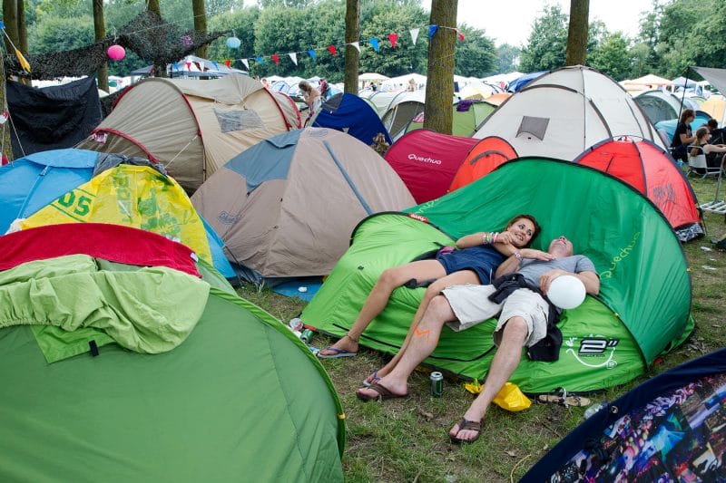 Lowlands festival gangers liggen op het campingterrein te geinen op een tent.